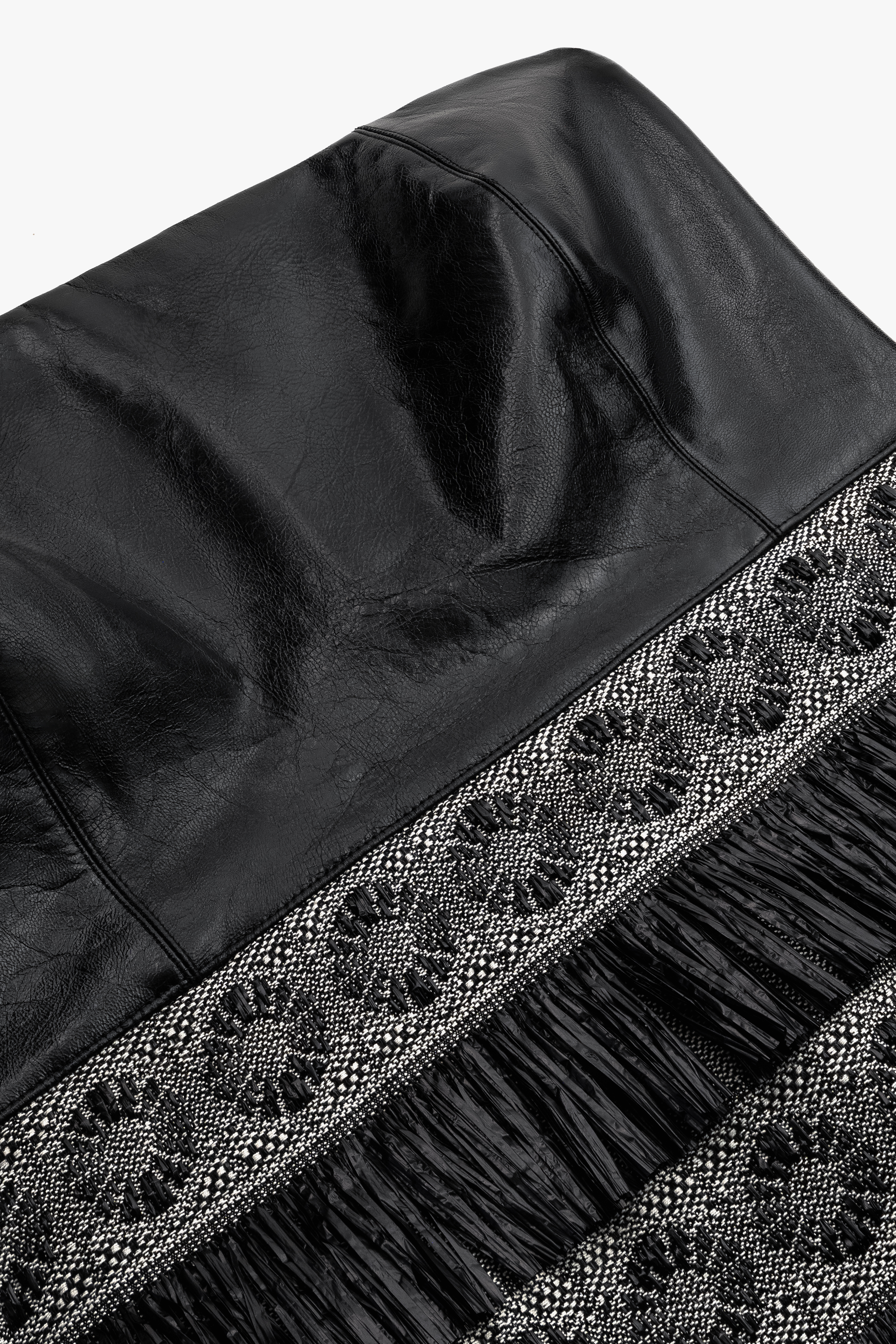 Close-up of luxurious black nappa leather texture and raffia detailing on the corset-style mini cocktail dress.